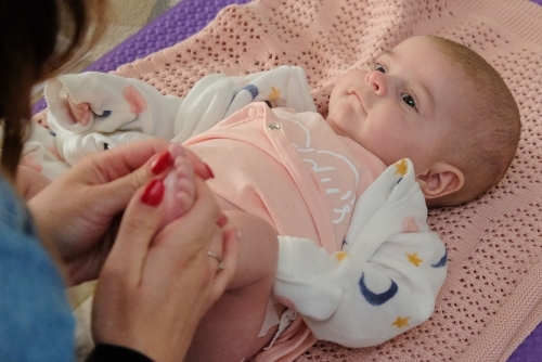 Family Hubs - Baby massage A baby laying on a mat having their foot massaged at one of our Family Hub baby massage sessions.