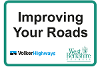 A sign with a green outline with the words 'Improving Your Roads' above the Volker Highways and West Berkshire Council logos.