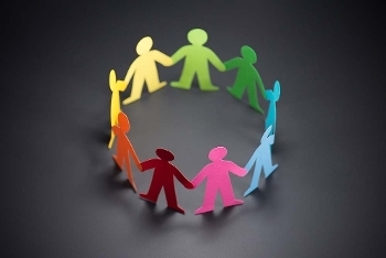 A circle of multi-coloured cut out paper people, holding hands.